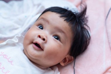 Sevimli bir Asyalı yeni doğmuş bebek, sevimli bir gülümsemeyle büyüleyici bir ev ortamında büyülüyor..