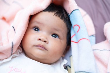 Yeni doğmuş Asyalı bir bebeğin masumiyet saçarak battaniyeye sarılı olduğu hassas bir an..