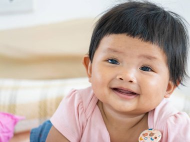 7-8 aylık gülümseyen bir kızın evde eğlendiği neşeli bir an..