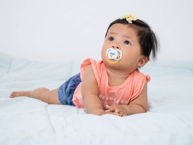 7-8 aylık neşeli bir kız bebek, aile sevgisi ve sıcaklığı ile çevrili yumuşak bir yatakta oynar..