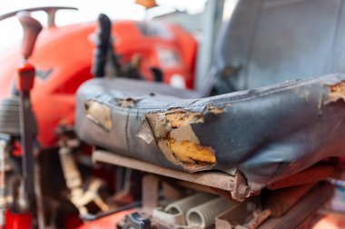 Görüntü, tarımsal çalışmaların yıpranmasını yansıtan bozulmakta olan bir traktör koltuğunu gösteriyor..