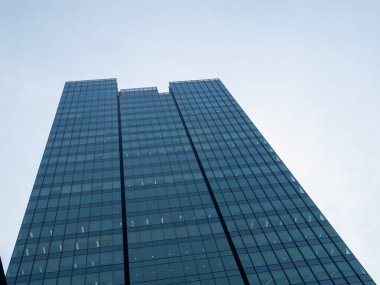 Çarpıcı bir modern gökdelen berrak bir gökyüzüne karşı parlak cam mimari sergiliyor..