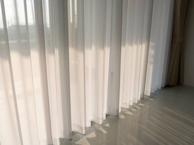 Parlak iç dizaynın perdeleri sakin bir ışık dolu atmosfer yaratıyor.