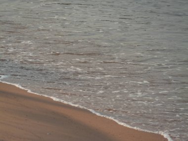 Huzurlu bir sahilde kıyıya vuran yumuşak dalgaların dinginliğini hisset..