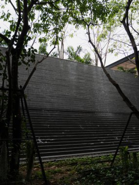 Çarpıcı bir modern mimari duvar çevreleyen yeşillikle kusursuz bir şekilde harmanlanır..