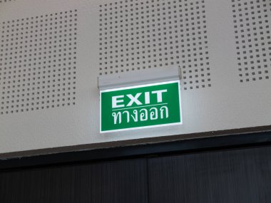 Aydınlatılmış bir çıkış işareti bireyleri güvenli bir kamu binasına yönlendirir.