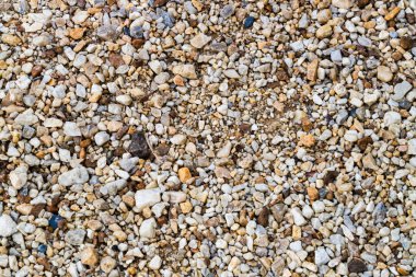 Bir inşaat alanındaki çeşitli doku ve renkleri vurgulayan çakıllı bir manzaranın yakın görüntüsü.