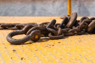 Sarı bir yüzey üzerinde duran ağır bir sanayi zincirinin yakın plan görüntüsü..