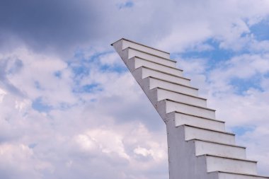 Göze çarpan bir merdiven tasarımı bulutlara doğru yükseliyor. Amaç ve yaratıcılığı simgeliyor..