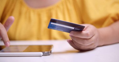 Bir kişi evden alışveriş yaparken kredi kartıyla güvenli bir ödeme yapar.