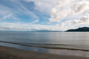 Huzurlu suların olduğu sakin bir sahil manzarası ve güzel bir gökyüzü altında hafif dalgalar..
