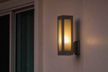 Şık bir duvar feneri, alacakaranlıkta sıcak bir parıltı yayar ve ev girişini estetiğe dönüştürür..