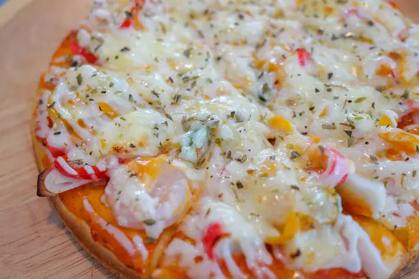 Sıcak bir mutfak ortamında canlı malzemelerle süslenmiş renkli peynirli pizzanın yakın çekim görüntüsü..