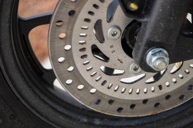 Bir garaj ayarında mekanik hassasiyet gösteren bir motosiklet fren diskinin karmaşık detaylarını araştırın..