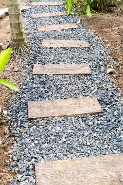 Güzel bir taş patika, açık havada doğal malzemeler ve sakin tasarım sergilenen bir bahçeye çıkıyor..