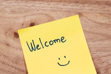 Neşeli bir hoş geldin notu ahşap bir masa sıcak ve davetkar bir ofis atmosferi yaratıyor..