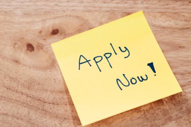 Parlak bir hatırlatma notu, iş başvuruları için işlem başlatır. Tahta bir masa.