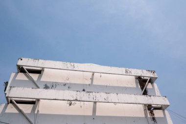 Terk edilmiş bir binanın ön cephesi, açık mavi gökyüzüne karşı kentsel bozulma ve mimari ayrıntı sergiliyor..