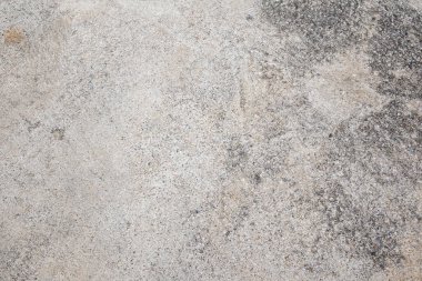 Bu resim yıpranmış beton bir yüzeyi gösteriyor. Karmaşık doku ve desenleri ortaya çıkarıyor..