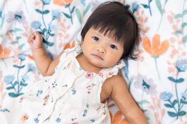 Bir Asyalı güzel bir kız rahat bir şekilde çiçekli bir battaniye çalıyor neşe ve masumiyet sergiliyor..