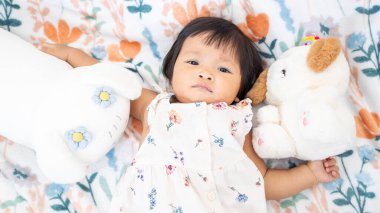 Bir yaşındaki Asyalı bir kızı en sevdiği peluş hayvanlarla oynarken yakalamak çok keyifli bir an..