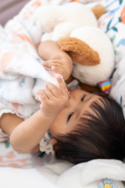 Neşeli bir Asyalı kız oyuncağına sarılıyor masumiyet ve neşe somutlaştırıyor.