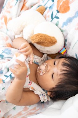 Çekici bir Asyalı kız çocuğu en sevdiği oyuncağıyla evin içinde oyun oynamaktan hoşlanıyor..