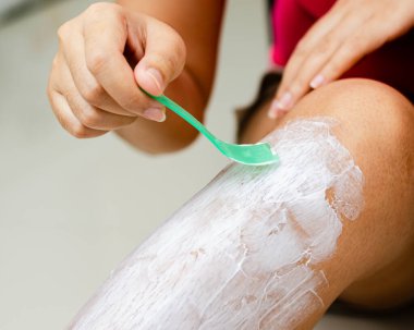 Bir kişi, evde etkili kılların alınması için balmumu benzeri bir madde uygular..