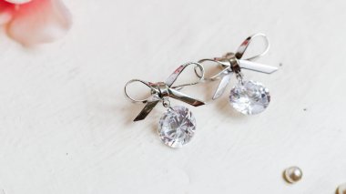 Parlak kristallerle süslenmiş bu zarif gümüş yay küpelerin cazibesini keşfedin..