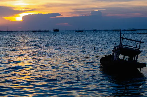 Güneş sakin suların üzerinde batarken, sakin ve yansıtıcı bir atmosfer yaratan yalnız bir tekne dinleniyor..