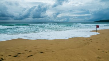 Sahile vuran dalgaların büyüleyici görüntüsü doğanın güzelliğini gözler önüne seriyor ve uyarı bayrağı uyarı işareti veriyor..