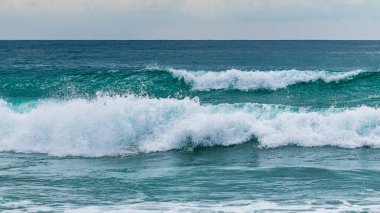 Sakin bir okyanus sahilinde dalgaları çarpıştırmanın huzur veren güzelliğini hissedin..