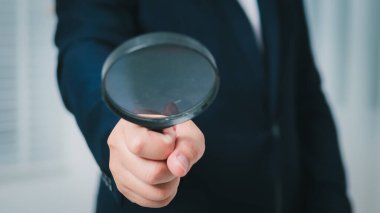 Bir profesyonel, odaklanma işinin önemini vurgulayan bir büyüteç kullanarak kritik detayları inceler.