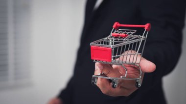 Bir işadamı, perakende sektörünün el seçimlerini sembolize eden bir alışveriş arabası sunuyor..