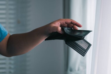 Bir kişi cüzdanını serin bir pencerenin yanında tutarken kişisel mali durumunu yansıtır.