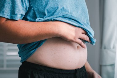 Bir insan elini dinlendirirken vücut değişimlerini yansıtır. Midesinde kişisel sağlık farkındalığı gösterir..