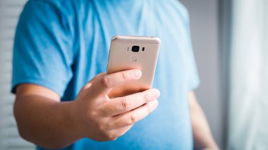 Bir insan evdeki akıllı telefonuyla iletişim kurarak modern teknolojiyi tanıtıyor. Sıradan bir ortam..