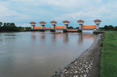 Bir su kapısı yapısı, sakin kırsal araziyi güzelleştirirken nehir akışını düzenleyen yüksek bir yapıda durur..