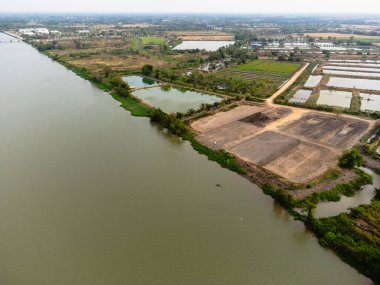 Doğanın ve sanayinin nehir kıyısı boyunca kesiştiğini gösteren bir hava manzarası..