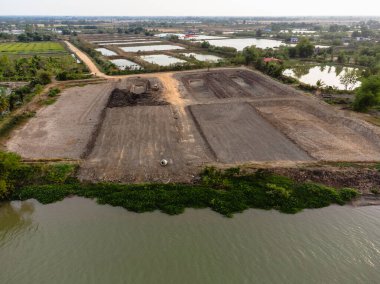Nehir kıyısında inşaat ve çevre değişikliklerinin gösterildiği havadan arazi geliştirme manzarası.