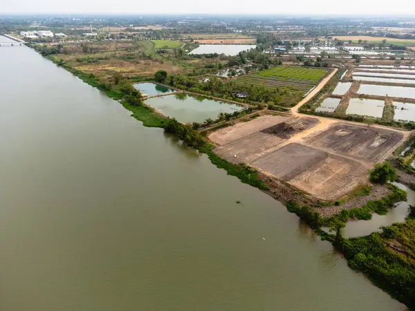 Doğanın ve sanayinin nehir kıyısı boyunca kesiştiğini gösteren bir hava manzarası..
