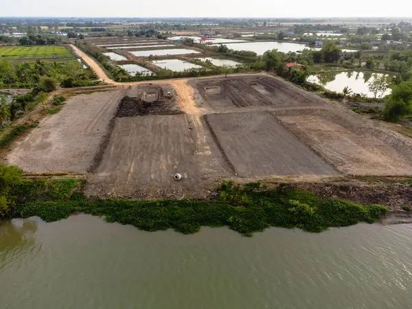 Nehir kıyısında inşaat ve çevre değişikliklerinin gösterildiği havadan arazi geliştirme manzarası.