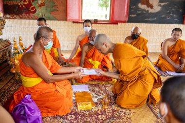 Chachoengsao, Tayland-13 Kasım 2023: Geleneksel Tayland dini törenine katılan genç bir keşiş Budist ayinlerine katılıyor.