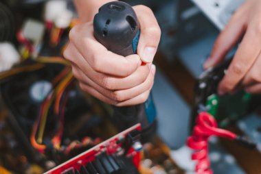 Bir teknisyen, elektronik aletleri ustalıkla matkap gösterici eller kullanarak tamir eder. Dağınık bir atölyede uzmanlaşır..