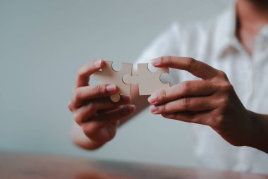 Yapboz parçaları olarak iş stratejisine el yaklaşımı takım çalışmasını ve işbirliğini sembolize eder..