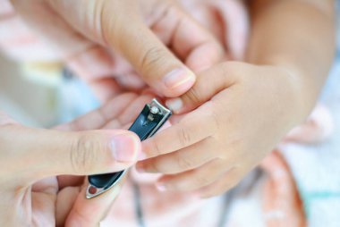 Bir ebeveyn, çocuğun tırnaklarını nazikçe keser. Günlük hayatı sevgi dolu ve şefkatli bir şekilde gösterir..