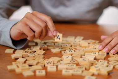 Odaklanmış bir el, yaratıcılık ve strateji içeren heyecan verici bir kelime oyunu olan bir harf seçer..