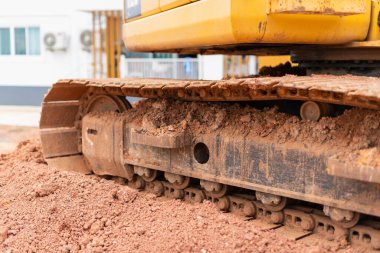 İnşaat alanında kazı makineleri çalışıyor. Ağır ekipman. Toprak yakın çekimde hareket ediyor.