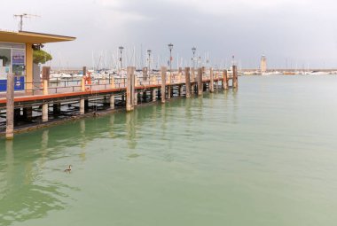 DESENZANO DEL GARDA, Italy - August 26, 2023: Pier on the lake Garda, with the marina and the lighthouse in the background
