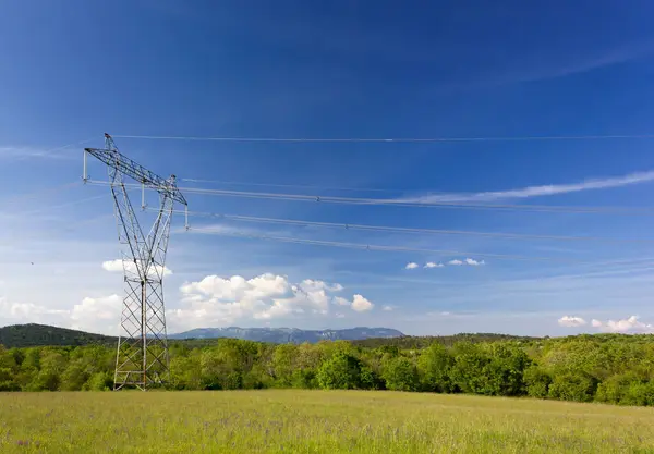 Green Field Blue Sky Electricity Pylon Foreground Hills Mountains Background Photo De Stock